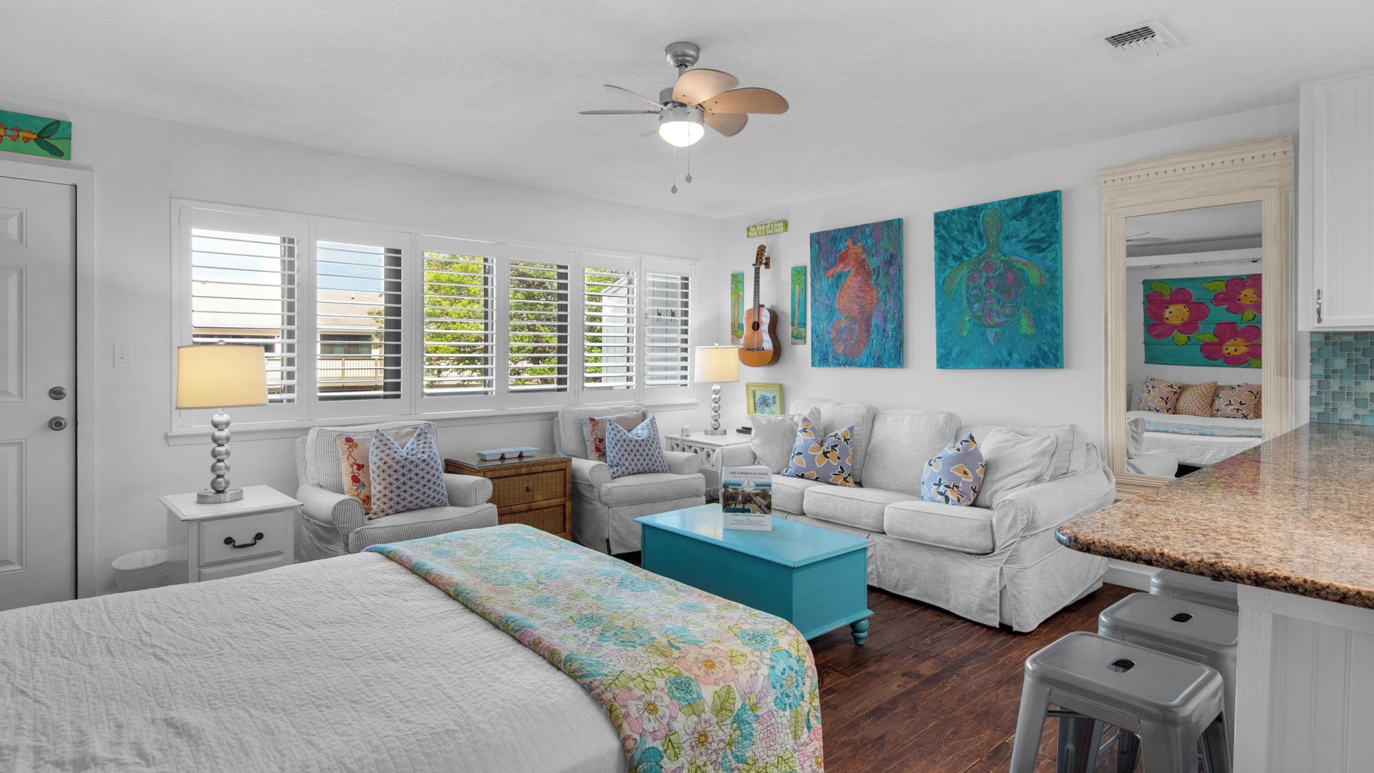 A bedroom with a bed, a sofa, a coffee table, and a ceiling fan.
