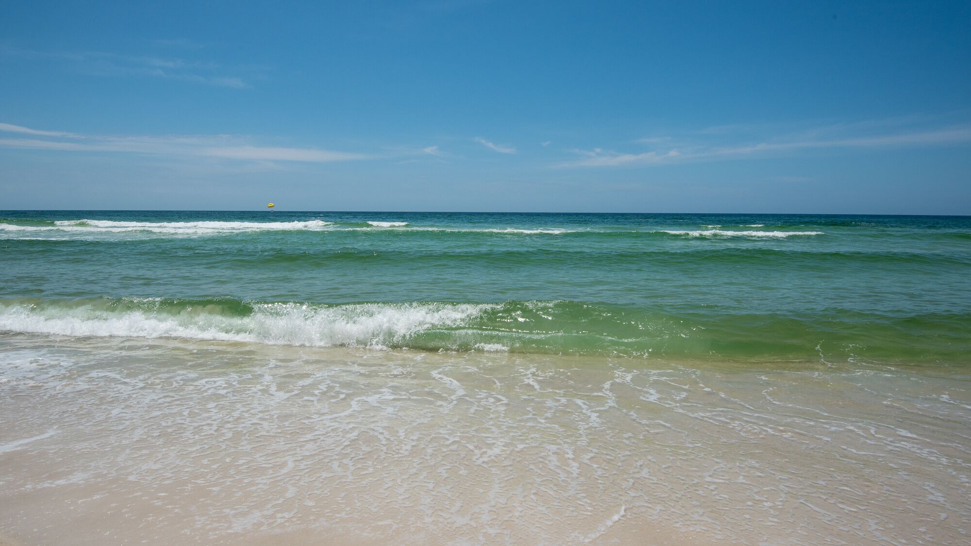 A beach with waves and a clear sky.