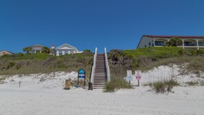 Un hotel frente a la playa con una escalera que lleva a un edificio de techo rojo.