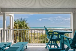 A covered outdoor area with a view of the beach, featuring a table and chairs.