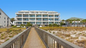 A multi-story hotel with a wooden boardwalk leading to the entrance.