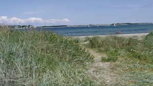 Une plage bordée de dunes herbeuses, offrant une vue dégagée sur la mer.