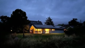 Une maison dotée d’un grand porche et dont l’intérieur est visible, avec une cheminée.