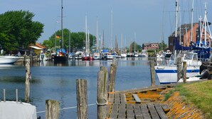 Un port de plaisance avec des bateaux amarrés, des passerelles en bois et un bâtiment en arrière-plan.