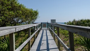 En träpromenad som leder till en strand, och där ett skylt anger att stranden endast är tillgänglig för fastighetsägare och deras gäster.