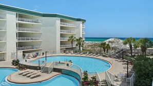 Un complejo turístico con piscina, varios balcones y vista al mar.