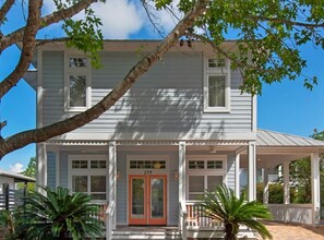 A two-story house with a porch, a red door, and a number '294' on the front.