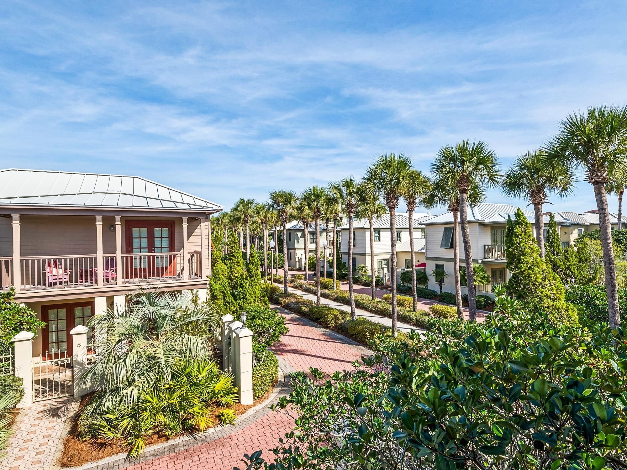 A residential area with a row of houses, a paved walkway, and palm trees.