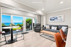 A modern living room with a sofa, armchairs, a coffee table, and a dining area with a table and chairs. - Gulf Front - Seagrove Beach + Free Attraction Tickets! (Santa Rosa Beach)