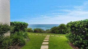Un sentier menant à une plage avec vue sur l’océan, bordé d’une végétation luxuriante.
