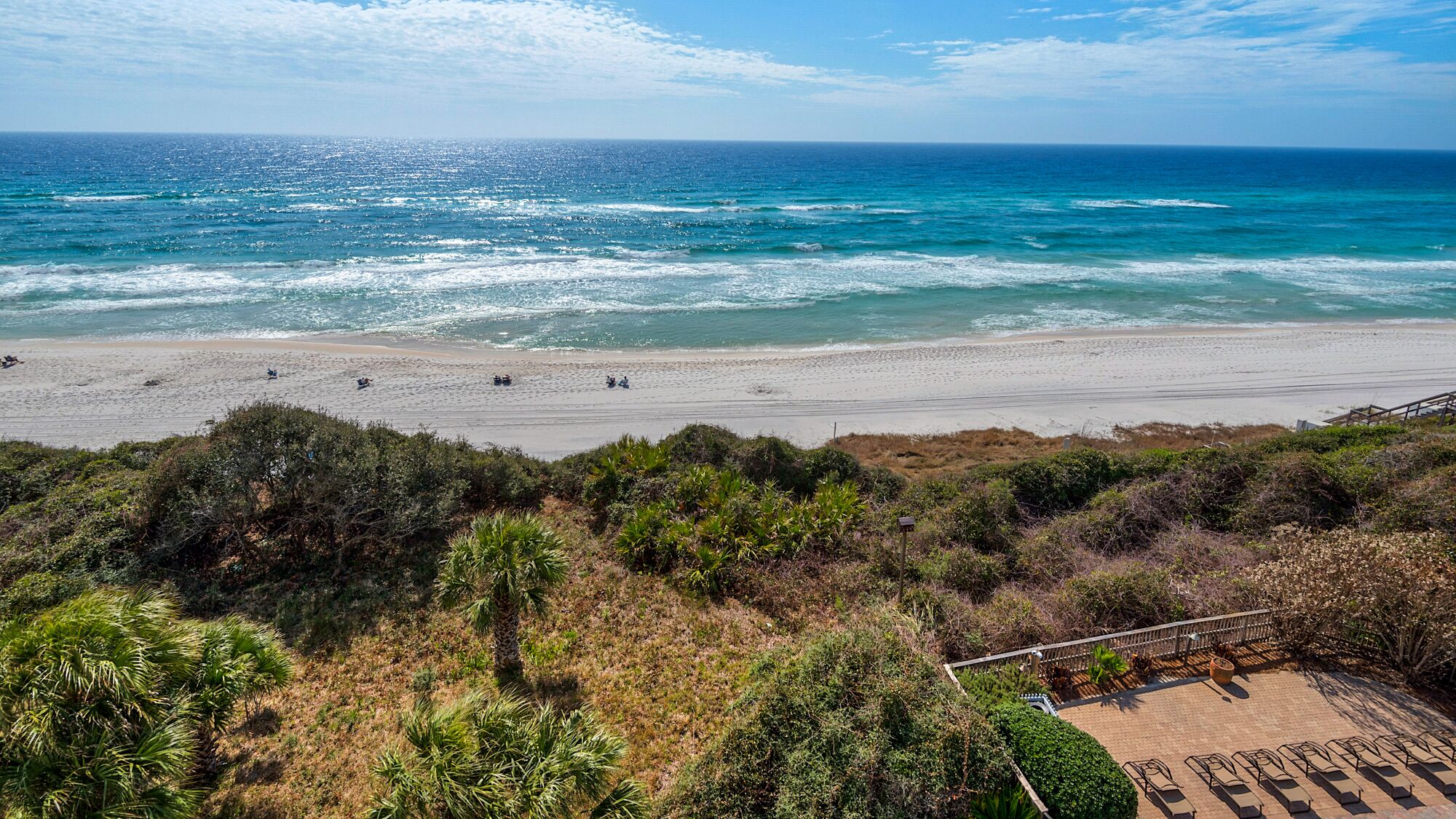 A beach with a sandy shore, a few people, and a view of the ocean.
