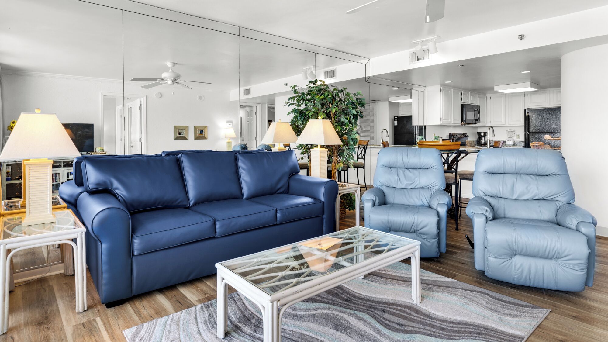 Uma sala de estar moderna com um sofá azul, uma mesa de centro de vidro e uma poltrona azul clara.