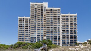 Un hotel de varios pisos con fachada uniforme, numerosos balcones y cielo despejado.