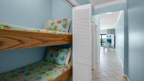Une chambre avec des lits superposés, une porte coulissante et une vue sur un balcon équipé de chaises.