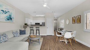 A modern living room with a grey sofa, a coffee table, and a dining area with a white table and chairs. - Seagrove Beach | Gulf Side + Free Tickets: Bikes, Dolphin Cruise & More! (Santa Rosa Beach)