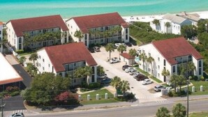 A coastal residential area with multiple buildings featuring red-tiled roofs, surrounded by greenery and a clear view of the ocean. - Seagrove Beach | Gulf Side + Free Tickets: Bikes, Dolphin Cruise & More! (Santa Rosa Beach)