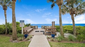 A wooden deck with benches leading to a beach, surrounded by palm trees and a clear blue sky. - Seagrove Condo with Pool Views Steps from the Beach + Free Attraction Tickets (Santa Rosa Beach)