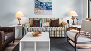 A living room with a striped sofa, two lamps, a white coffee table, and a wall painting. - Seagrove Condo with Pool Views Steps from the Beach + Free Attraction Tickets (Santa Rosa Beach)