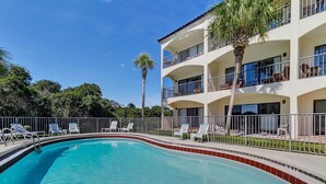 A multi-story hotel with a swimming pool, outdoor seating, and palm trees. - Seagrove Condo with Pool Views Steps from the Beach + Free Attraction Tickets (Santa Rosa Beach)