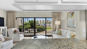 Ein Hotelzimmer mit Balkon, Fernseher, Esstisch und einer Couch.