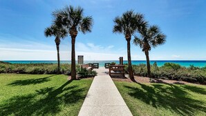 A pathway leading to a beach with palm trees and wooden benches. - Modern 1st-Floor Condo with Gulf Views + Free Attraction Tickets! (Santa Rosa Beach)