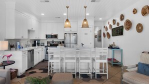 A modern kitchen with white cabinetry, stainless steel appliances, and a central island with seating. - Modern 1st-Floor Condo with Gulf Views + Free Attraction Tickets! (Santa Rosa Beach)