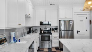 A modern kitchen with white cabinetry, stainless steel appliances, and a marble countertop. - Modern 1st-Floor Condo with Gulf Views + Free Attraction Tickets! (Santa Rosa Beach)