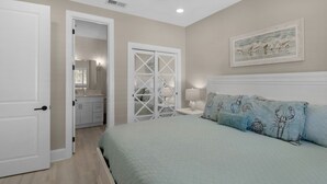 Un dormitorio con cama, mesita de noche, cómoda y armario con puerta de espejo.