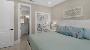 A bedroom with a bed, a nightstand, a dresser, a closet, and a painting on the wall.