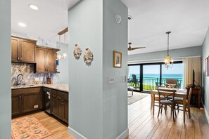 A kitchen with wooden cabinets, a marble countertop, and a dining area with a table and chairs.