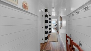 A hallway with white paneling, a black and white striped curtain, and a wooden floor. - Direct Gulf views & access to the sparkling waters + Free Attraction Tickets! (Santa Rosa Beach)