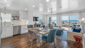 A spacious kitchen with modern appliances, a dining area with clear chairs, and a living area with a view of the beach. - Direct Gulf views & access to the sparkling waters + Free Attraction Tickets! (Santa Rosa Beach)