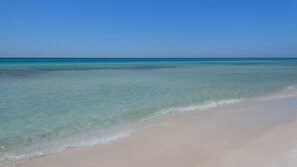 Een strand met helder turquoise water en een zandstrand.