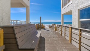 Una terraza de madera que da a una playa con vista despejada al océano.