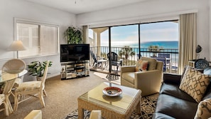 Enjoy unobstructed ocean views from this spacious living room with a sofa, chairs, flat-screen TV, and a coffee table.