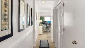 A hallway with framed pictures, a dining area with a view, and a door with shutters. - Gulf-Front, Pool in Seagrove, Next Door to Seaside + Free Attraction Tickets! (Santa Rosa Beach)