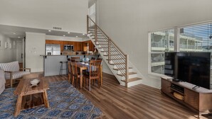 A modern living room with a wooden coffee table, a TV stand, and a staircase leading to an upper level.
