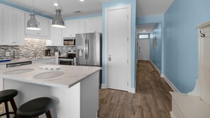 A modern kitchen with white cabinets, stainless steel appliances, and a marble island.