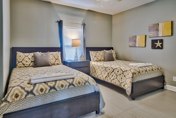 Un dormitorio con dos camas, una mesita de noche, una lámpara y decoración en la pared.