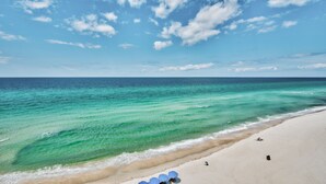 Une plage aux eaux turquoise et limpides, bordée d’un rivage sablonneux.