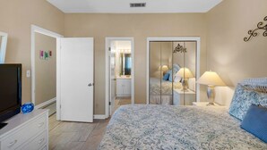 A bedroom with a bed, bedside lamps, a dresser, and a mirror.