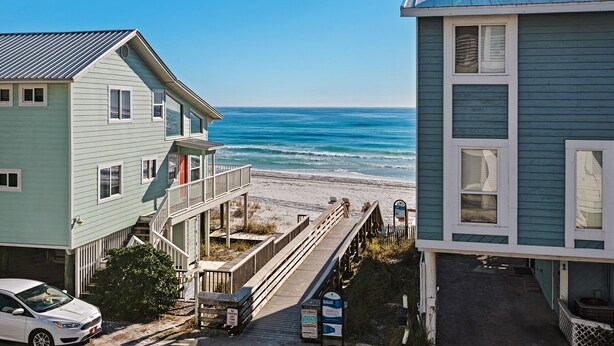 A coastal house with a wooden deck and a view of the ocean. - Dog-Friendly Gulf Side Cottage, 6 Mins to Beach, Pool, Bikes + Free Tickets! (Santa Rosa Beach)