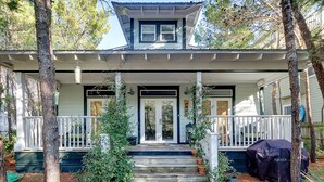 A two-story house with a porch, a covered front door, and a small upper deck. - Dog-Friendly Gulf Side Cottage, 6 Mins to Beach, Pool, Bikes + Free Tickets! (Santa Rosa Beach)