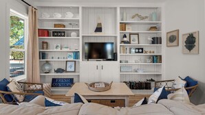 Una sala de estar con televisor, estanterías y un letrero que dice "FRESH OYSTERS".