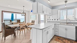 A modern kitchen with white cabinets, a large island, and a view of the ocean. - Gulf Front, Steps to Beach, Sleeps 11 + Attraction Tickets! (Inlet Beach)