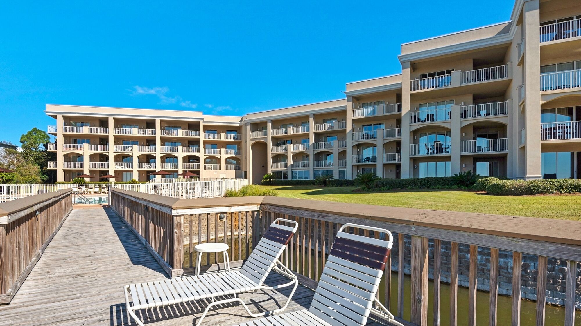 Un hôtel à plusieurs étages doté de balcons, d’un espace piscine et d’une promenade en bois avec des chaises longues.