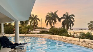 A swimming pool with lounge chairs and a view of palm trees and a building in the background. - Shell House, Dominican Caracol with 14m Pool and Ocean view (Cabrera Maria Trinidad Sanchez)