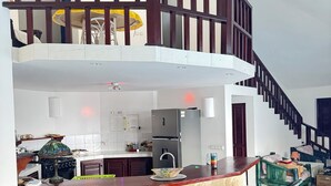 A spacious kitchen with a central island, a dining area with bar stools, and a staircase leading to an upper level. - Shell House, Dominican Caracol with 14m Pool and Ocean view (Cabrera Maria Trinidad Sanchez)