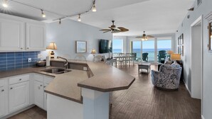 Una cocina moderna con una isla grande, armarios blancos y vista al océano.