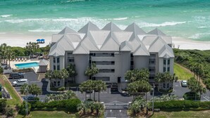 Un hotel de varios pisos con piscina, rodeado de palmeras y una playa.